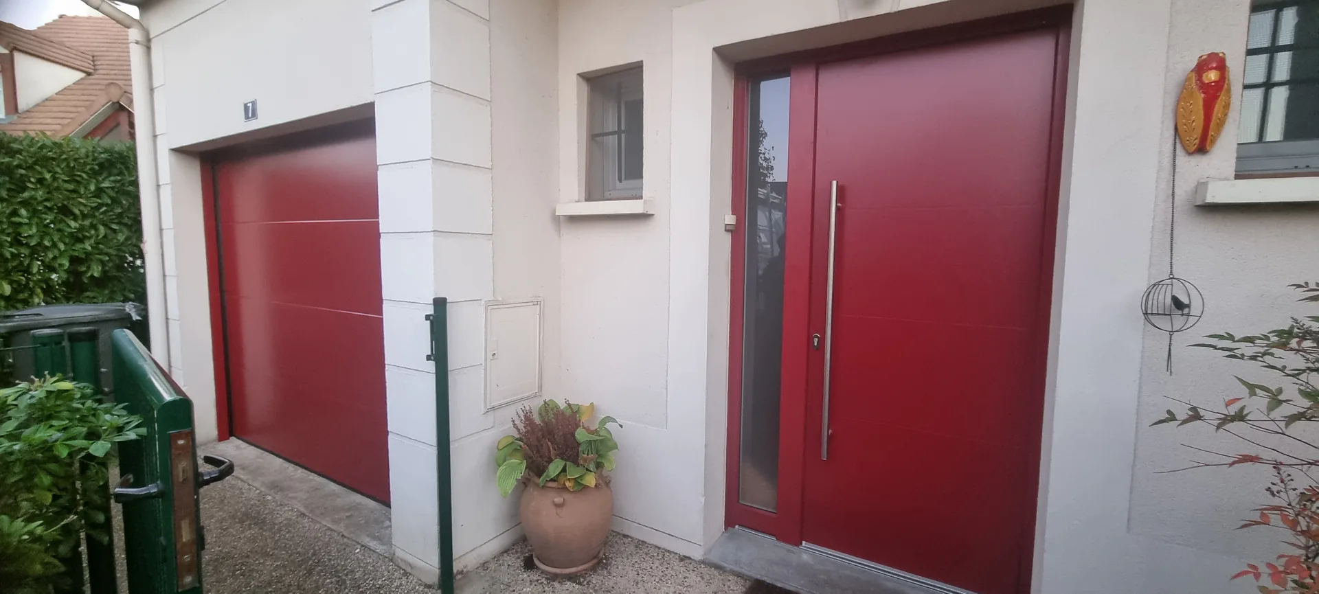 Porte de garage sectionnelle rouge motorisée avec porte d'entrée assortie